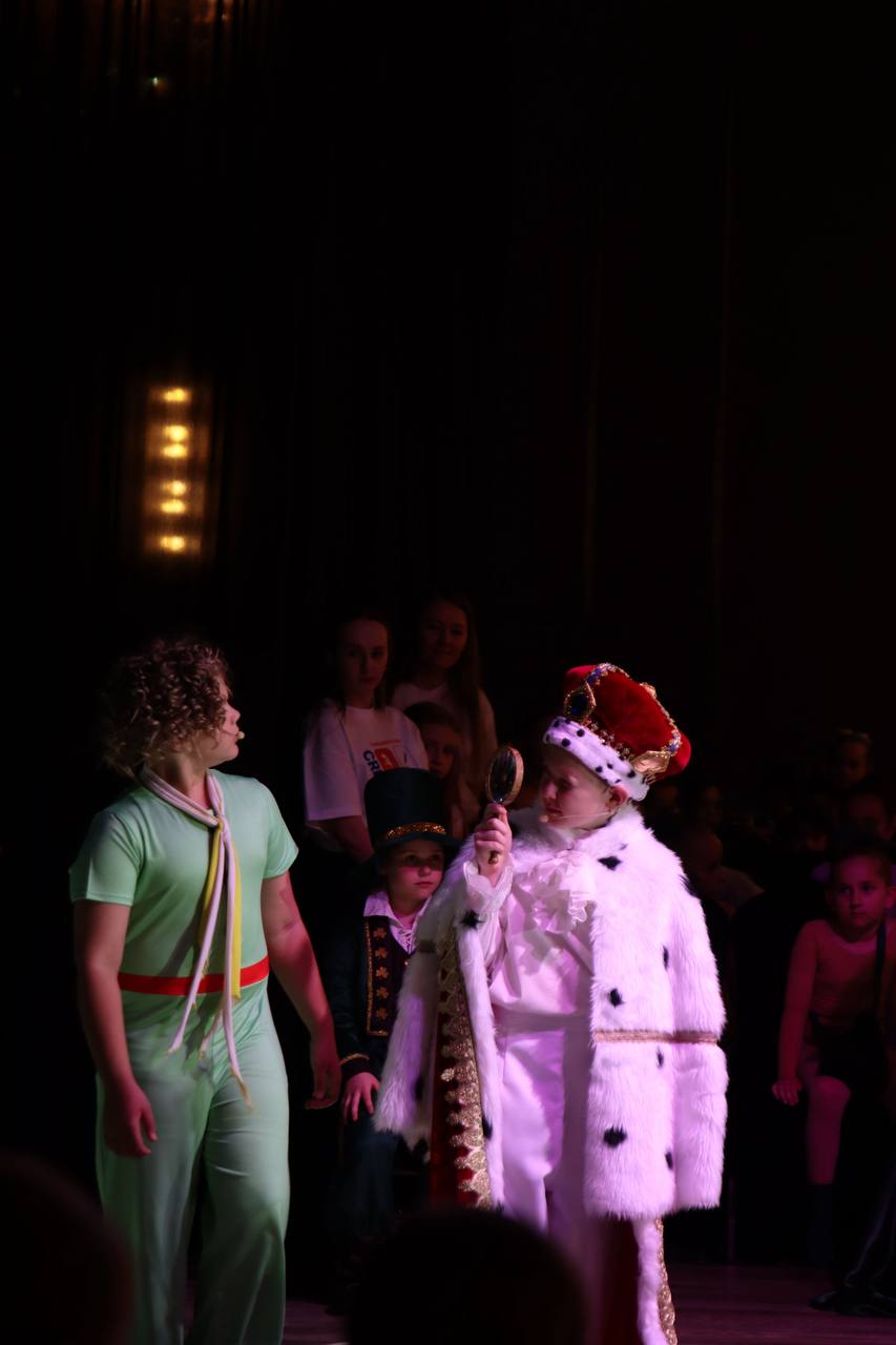 A theatrical performance with a young actor in a crown and royal costume